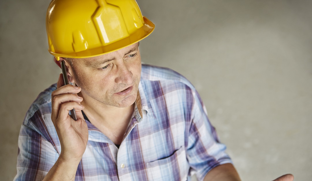 Senior carpenter is using mobile phone